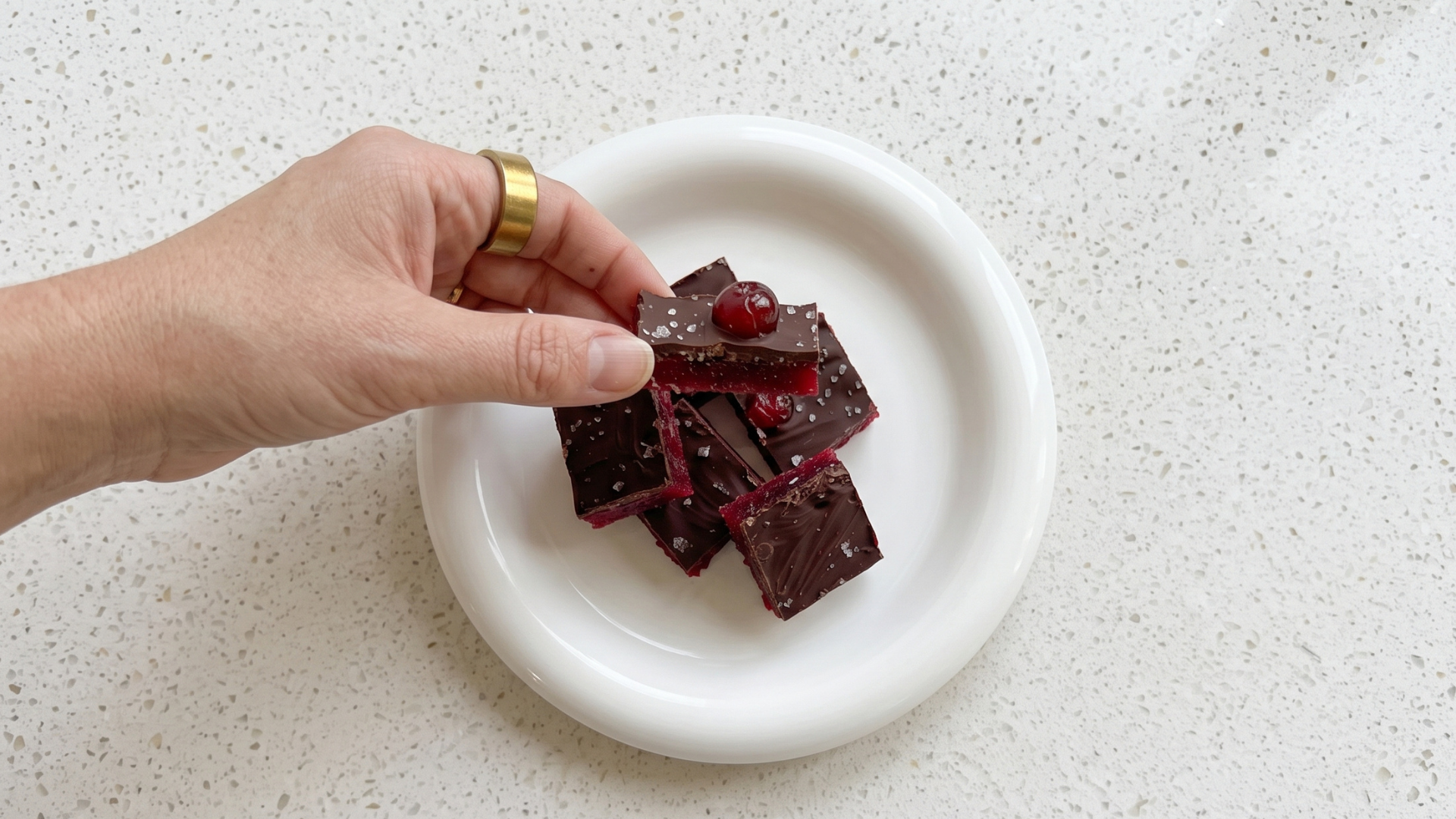 Chocolate cherry collagen slice pieces topped with fresh cherries on a white plate